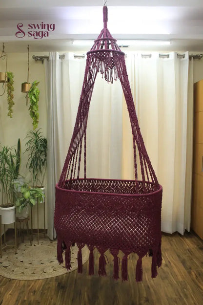 Brick Colored macrame baby bassinet hanging in an indoor setting.