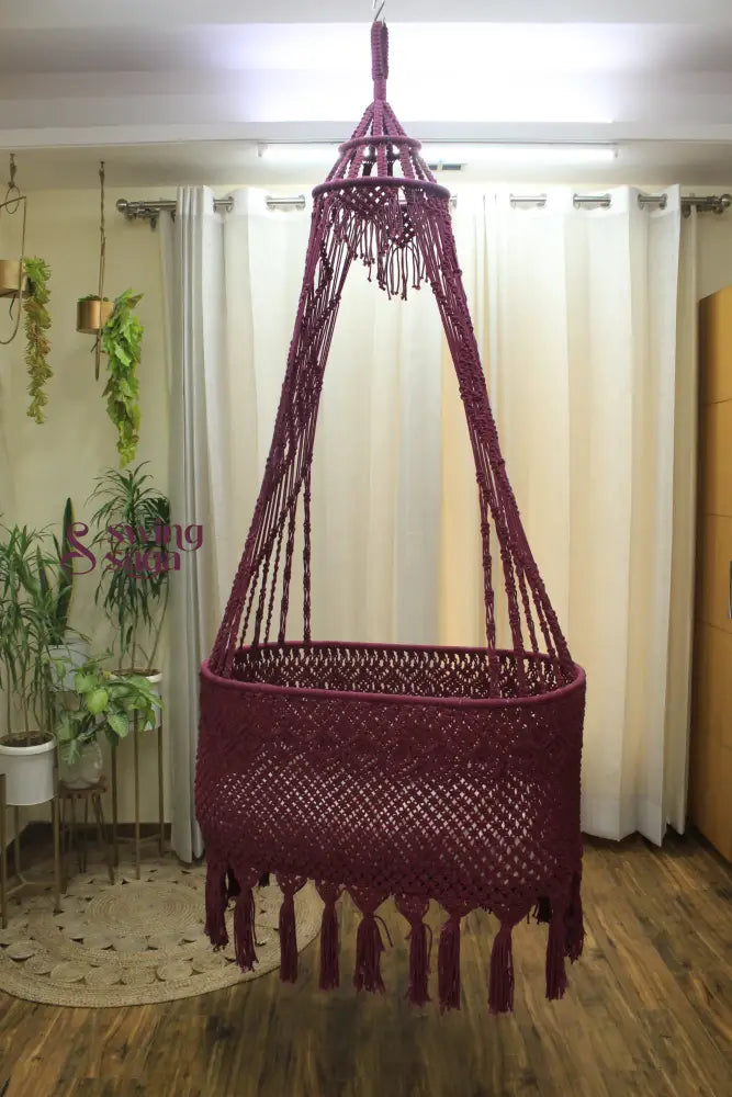 Brick Colored macrame baby bassinet hanging in an indoor setting.