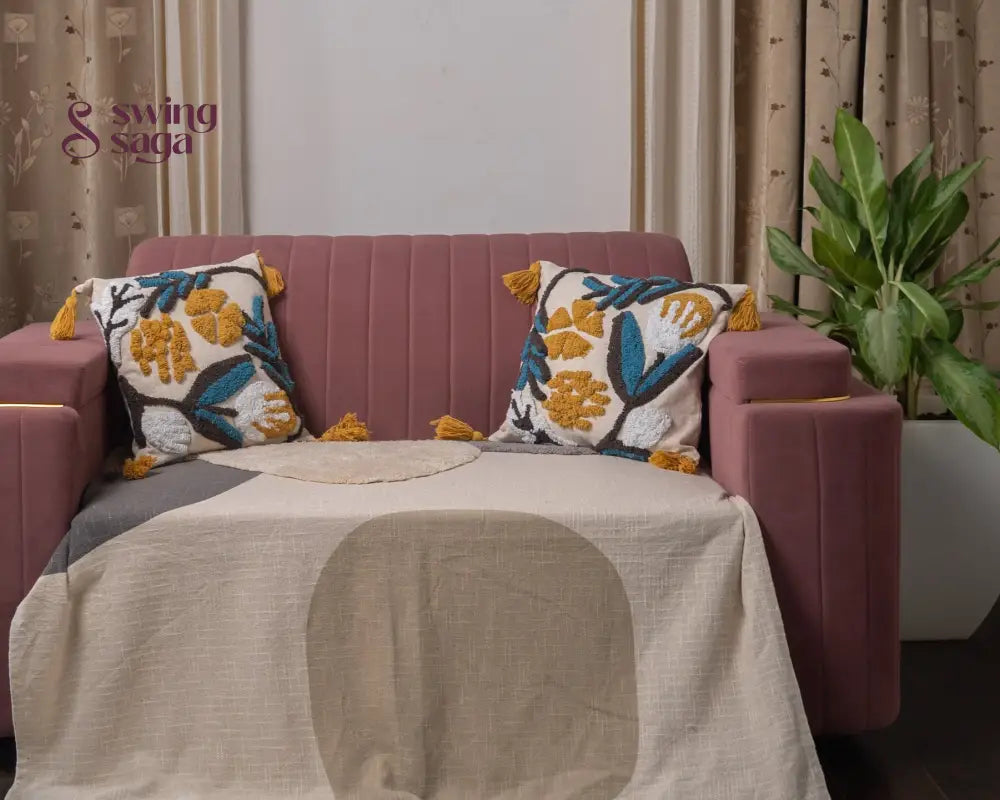 Pink sofa with decorative pillows and a blanket in a room with curtains and a plant.
