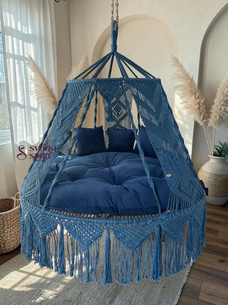 Blue macrame hanging chair with cushions in a room with natural light