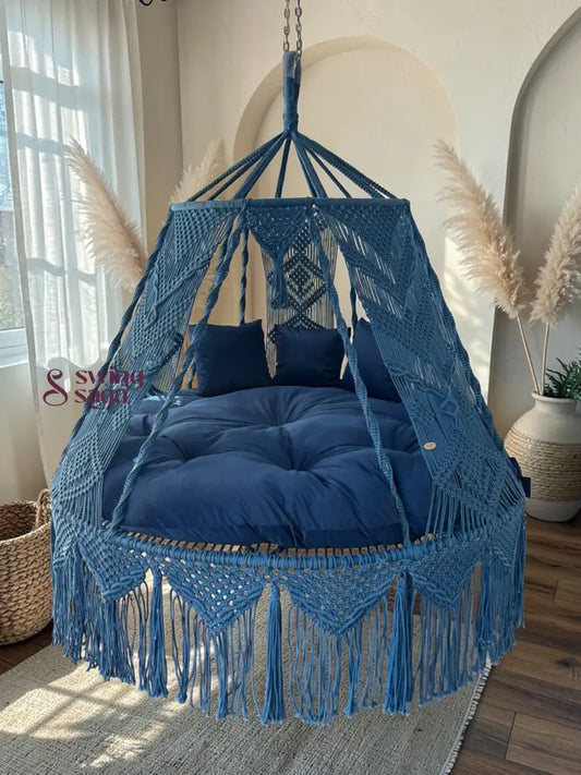 Blue macrame hanging chair with cushions in a room with natural light