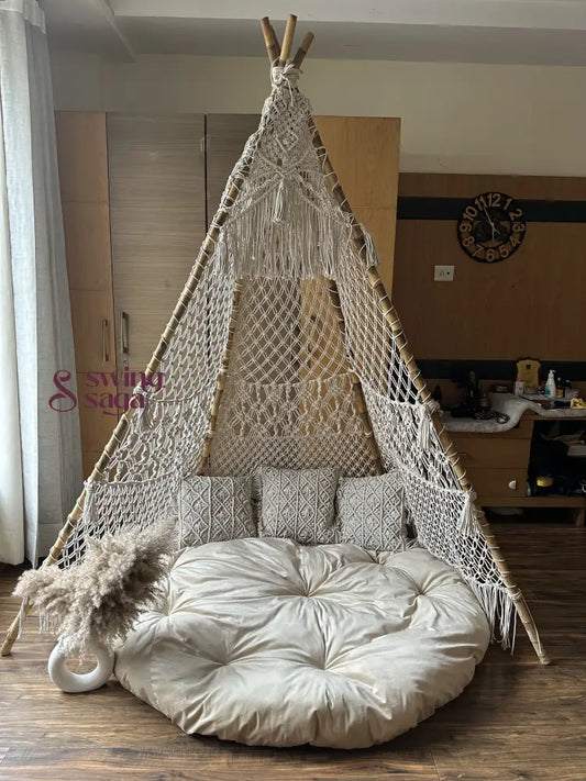 white handmade macrame teepee with white mattress and 3 small square cushions.