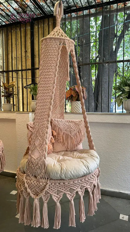 Single seater macrame hanging swing with two square shaped cushions.