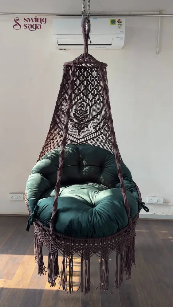 Hanging macrame chair with green cushion in a room with an air conditioner.