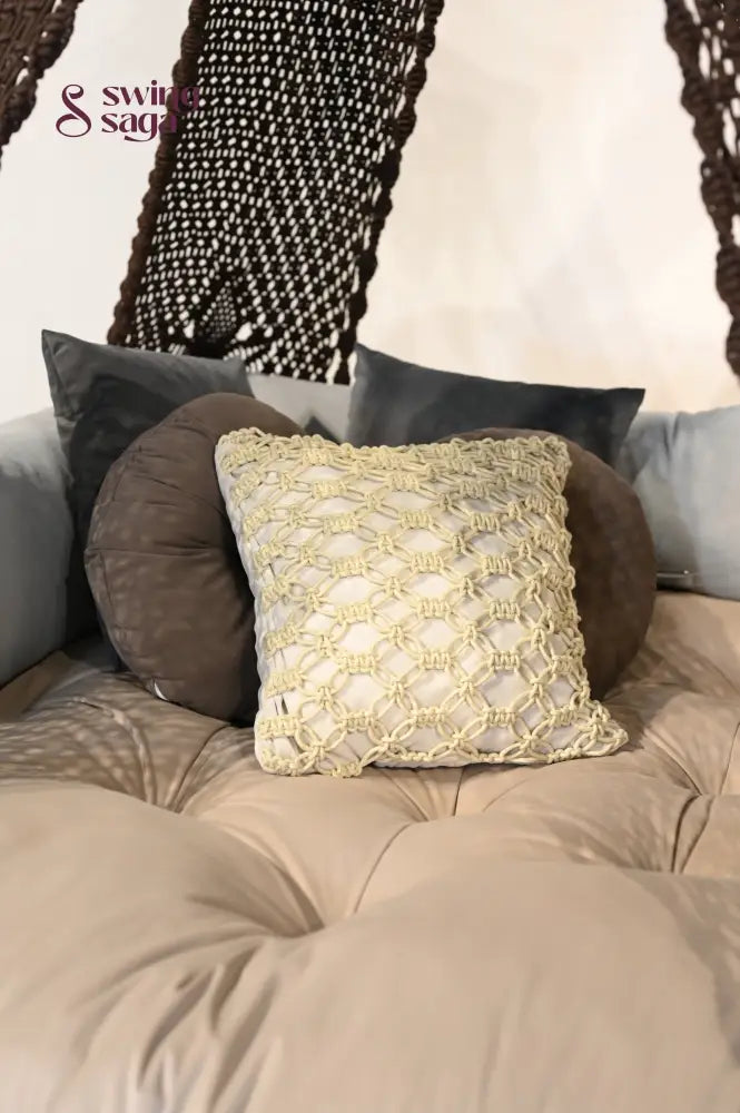 Macrame cushions in ivory color with other cushions on a mattress. 