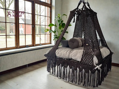Coke colored square bed swing in an indoor setting, with plush round cushions. 