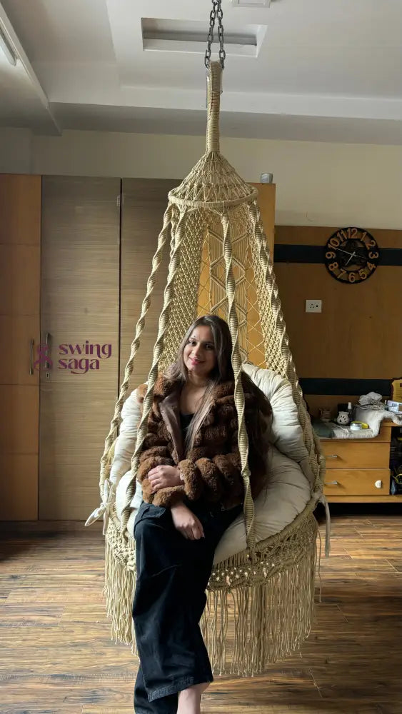 A girl is sitting on a macrame chair hammock swing