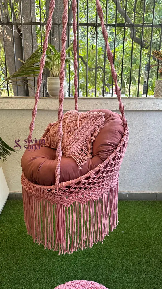 Small pink macrame swing chair in an indoor balcony setting
