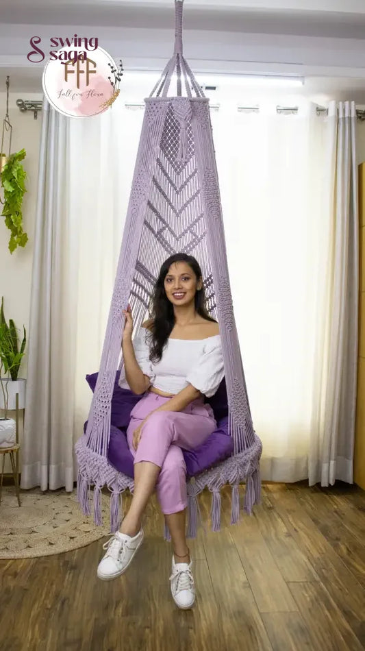 A girl is sitting on a lavender macrame swing chair.