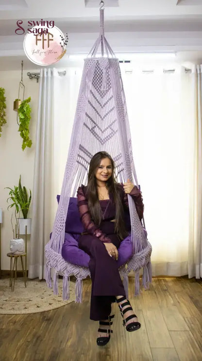 A girl is sitting on a purple chair hammock hanging swing.