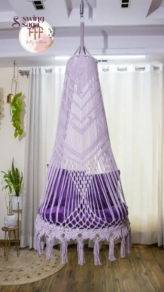 hanging macrame chair swing in purple color with mattress and cushions.