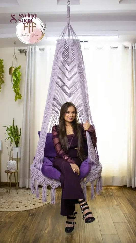 A girl is sitting on a purple chair hammock hanging swing.