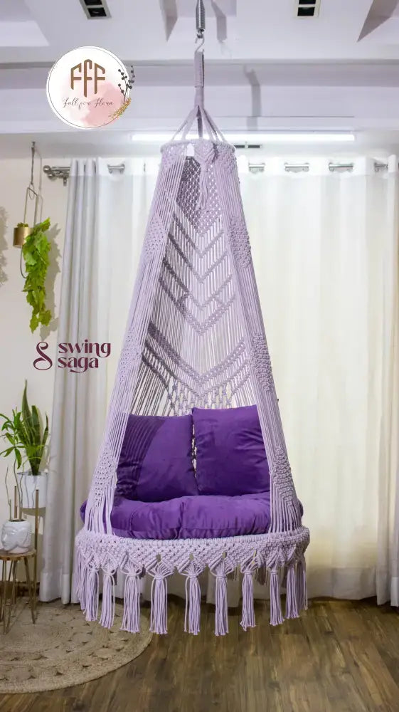 hanging macrame chair swing in purple color with mattress and cushions.