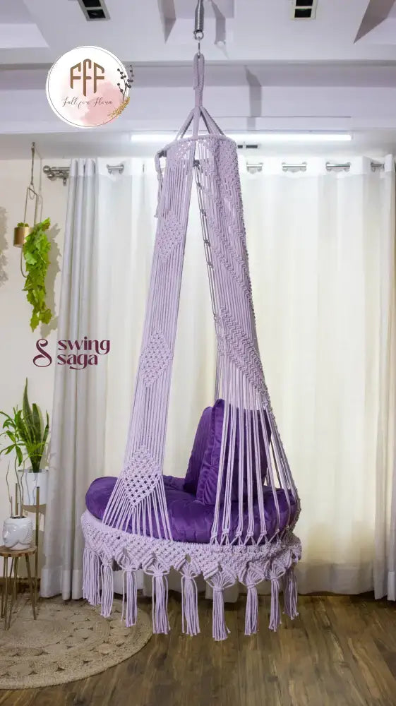 hanging macrame chair swing in purple color with mattress and cushions.