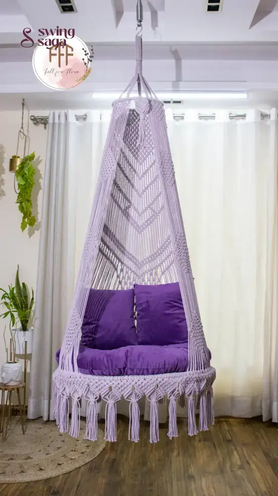 hanging macrame chair swing in purple color with mattress and cushions.