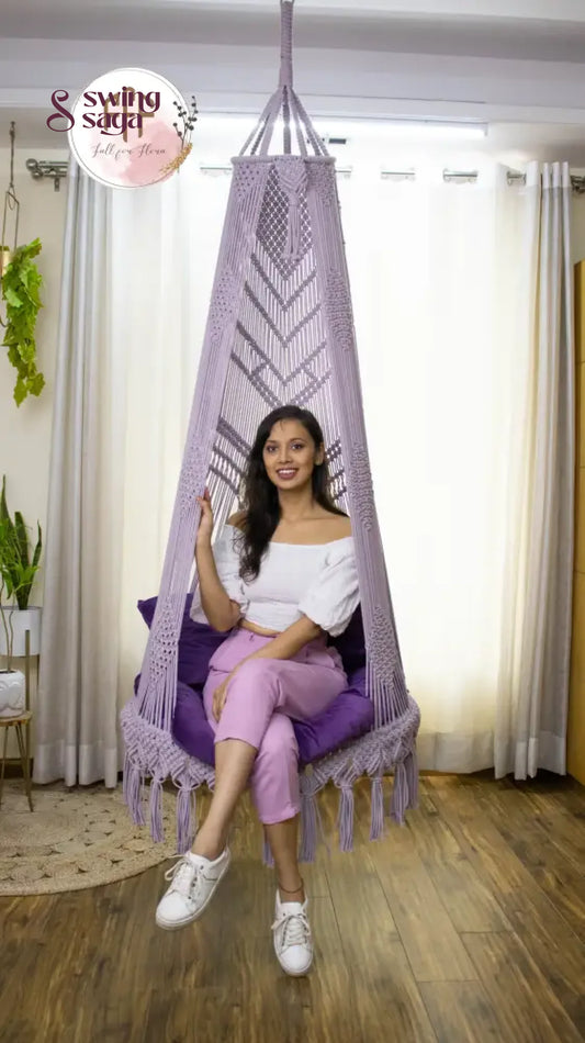 A girl is sitting on a lavender macrame swing chair.