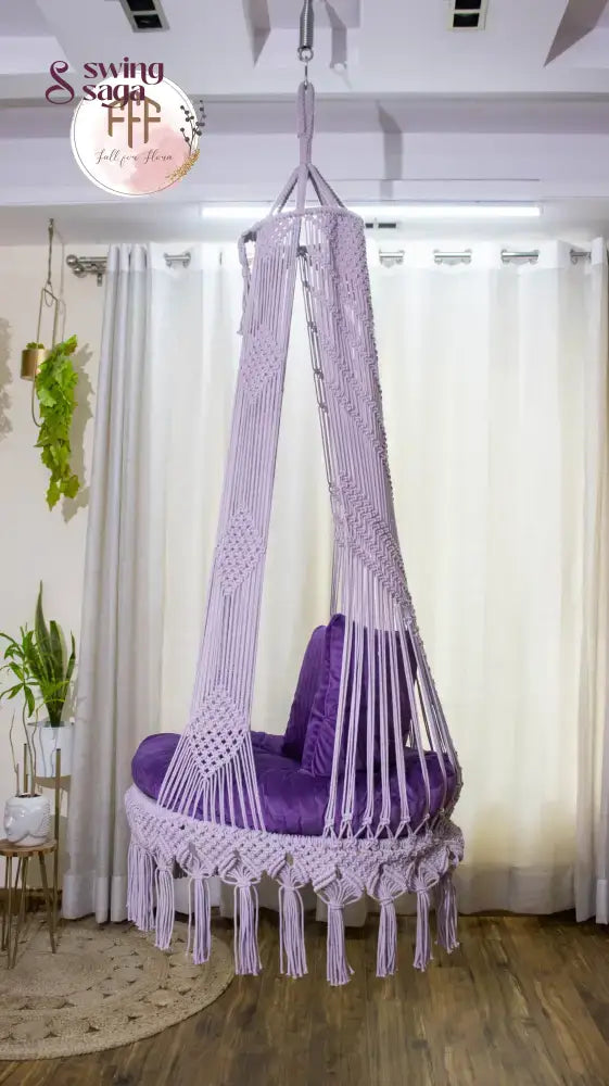hanging macrame chair swing in purple color with mattress and cushions.