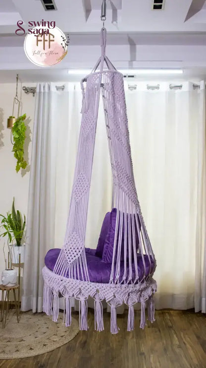 hanging macrame chair swing in purple color with mattress and cushions.