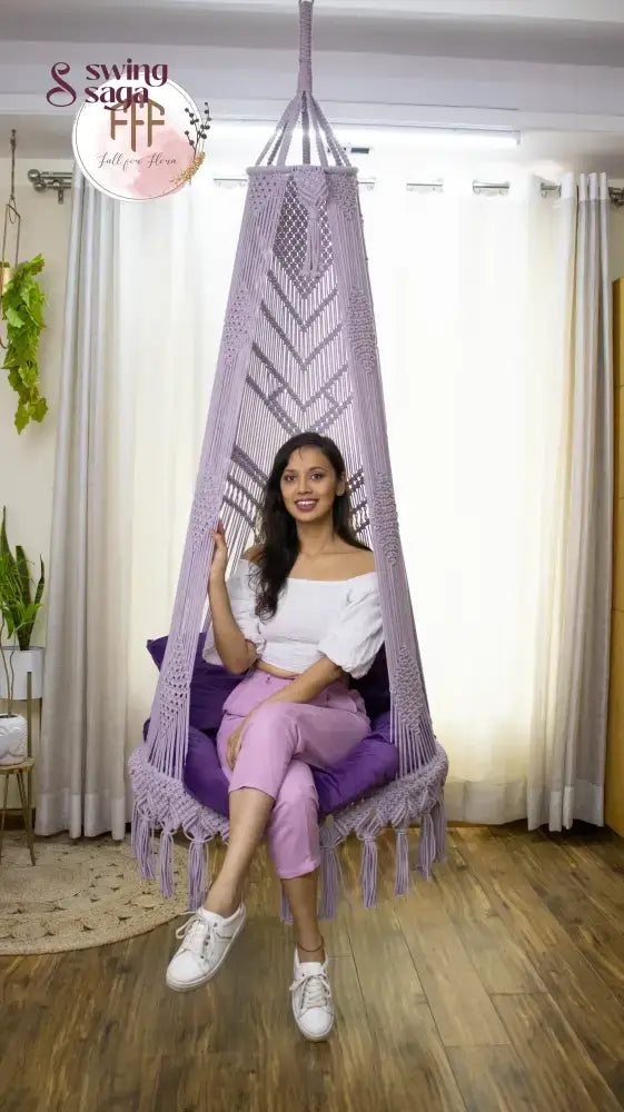A girl is sitting on a lavender macrame swing chair.