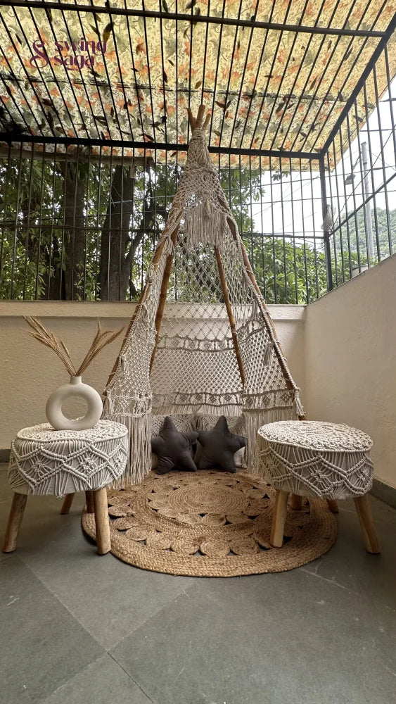 Handmade macrame teepee in white color placed in an outdoor setting.