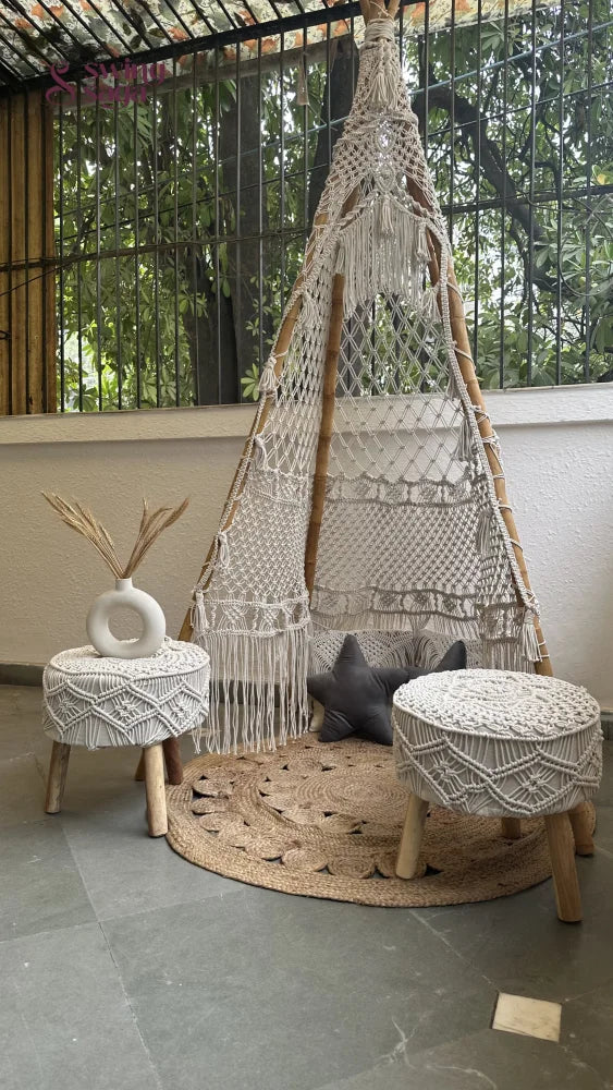 Handmade macrame teepee in white color placed in an outdoor setting.