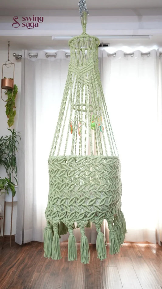 Side image of a lime green colored macrame baby cradle in a room setting.