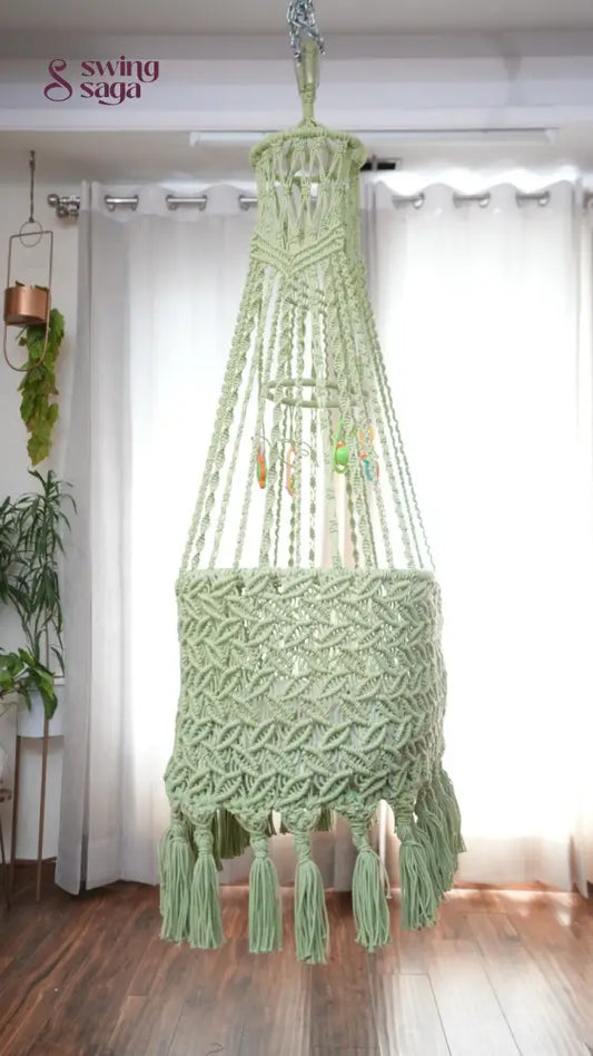 Side image of a lime green colored macrame baby cradle in a room setting.