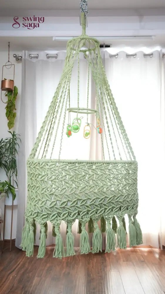 A lime green colored macrame baby cradle in a nursery room.