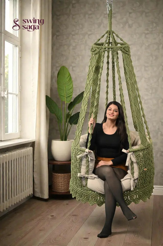 A girl is sitting on a macrame hammock chair.