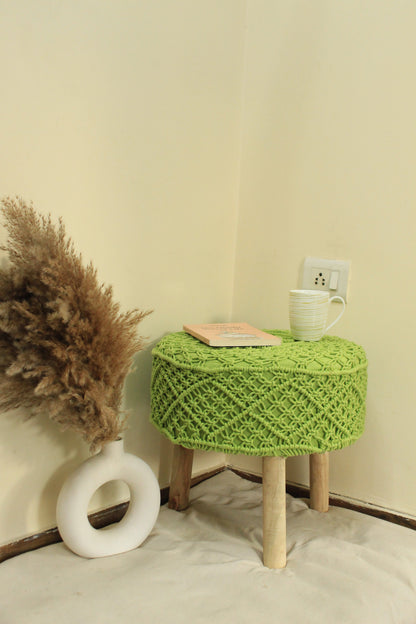 Round green macrame ottoman featuring intricate handwoven design and natural wooden legs