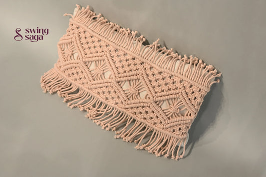 Macrame wall hanging with geometric pattern and fringe on a plain background