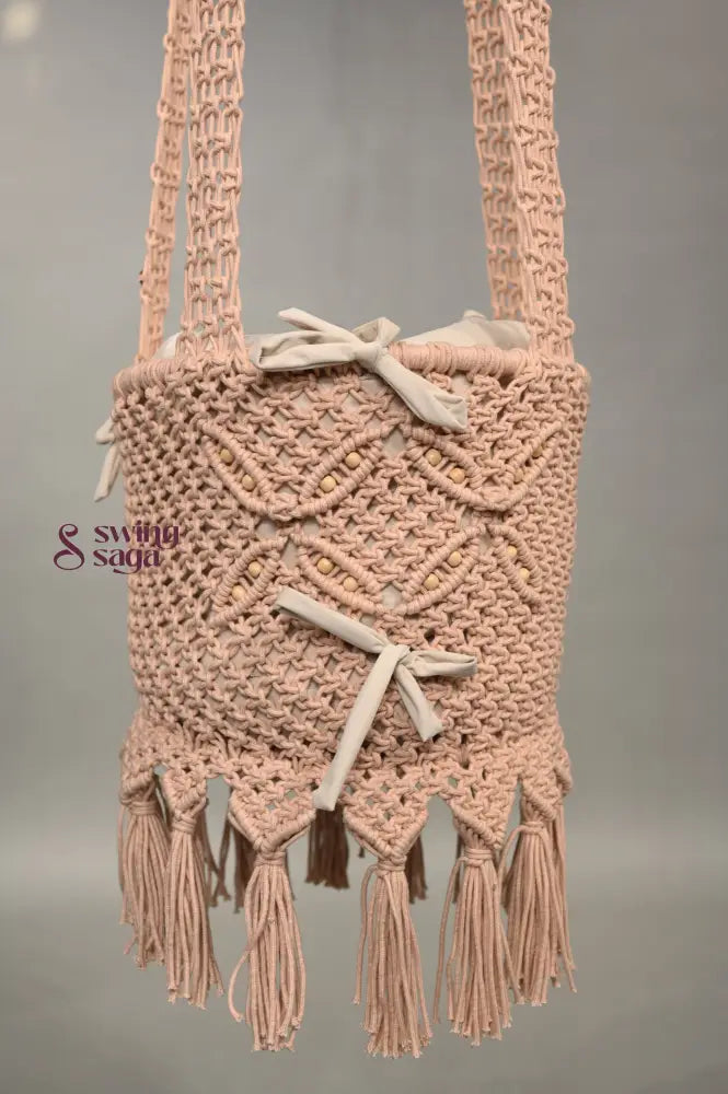 Macrame baby swing with tassels on a plain background
