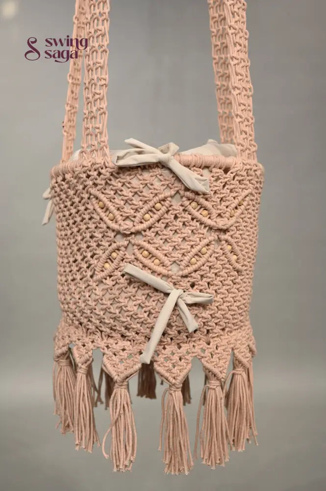 Macrame baby swing with tassels on a plain background