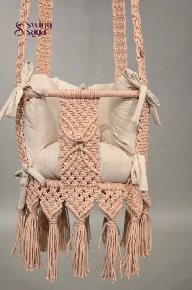 Macrame baby swing with tassels on a plain background