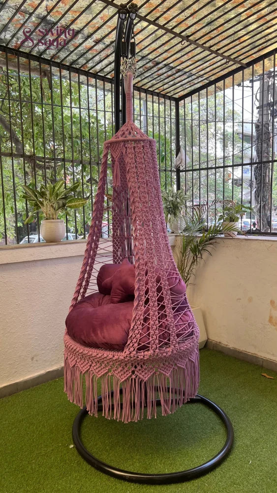 pink macrame swing with a metal stand.