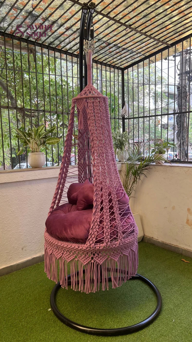 pink macrame swing with a metal stand.