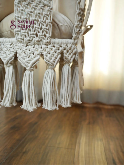 Image of macrame baby swing with tassels in a room with wooden flooring.