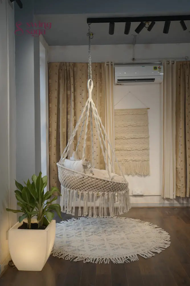 round chair hammock swing in white color with cream mattress and a star cushion.