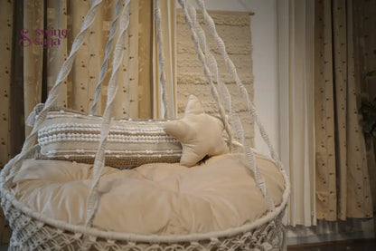Cream hanging hammock swing with mattress and cushions.