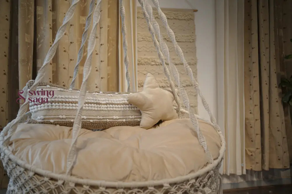 Cream hanging hammock swing with mattress and cushions.