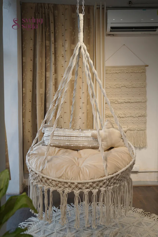 round chair hammock swing in white color with cream mattress and a star cushion.