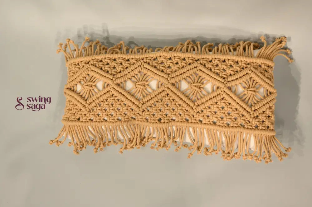 Decorative macrame wall hanging with geometric pattern and fringes on a plain background