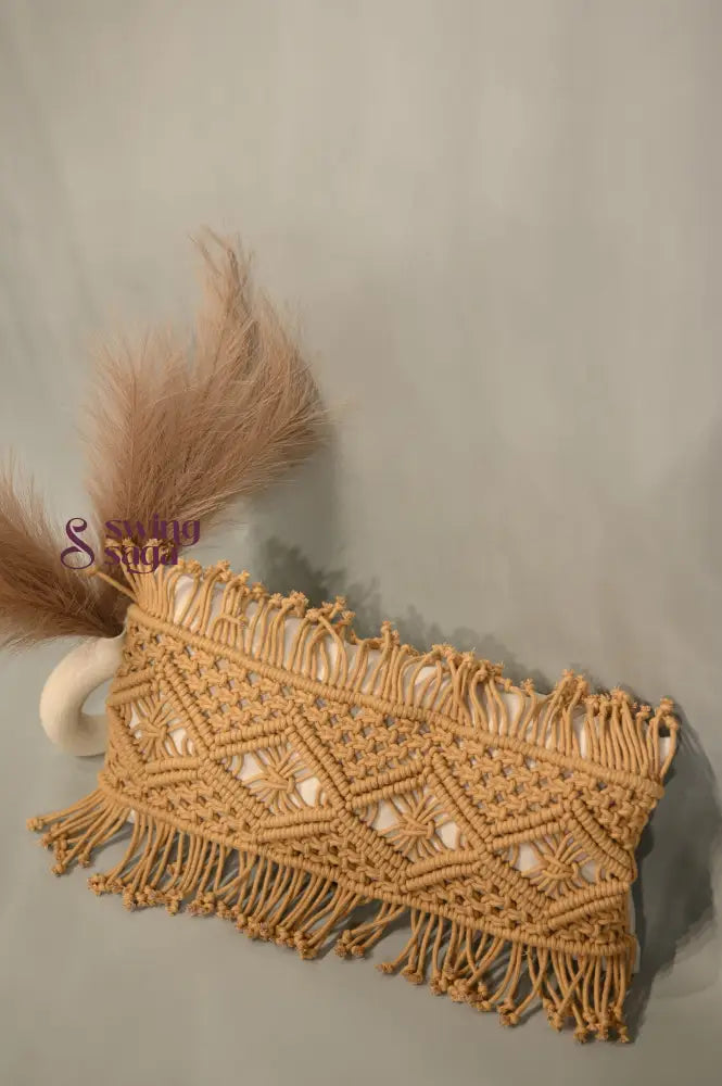 Macrame clutch with fringes and feathers on a neutral background