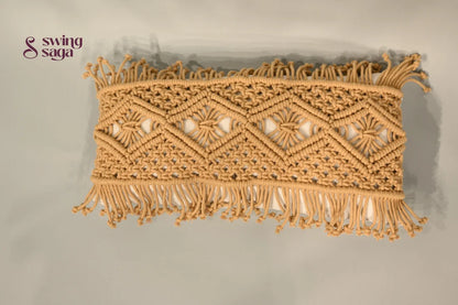 Decorative macrame wall hanging with geometric pattern and fringes on a plain background
