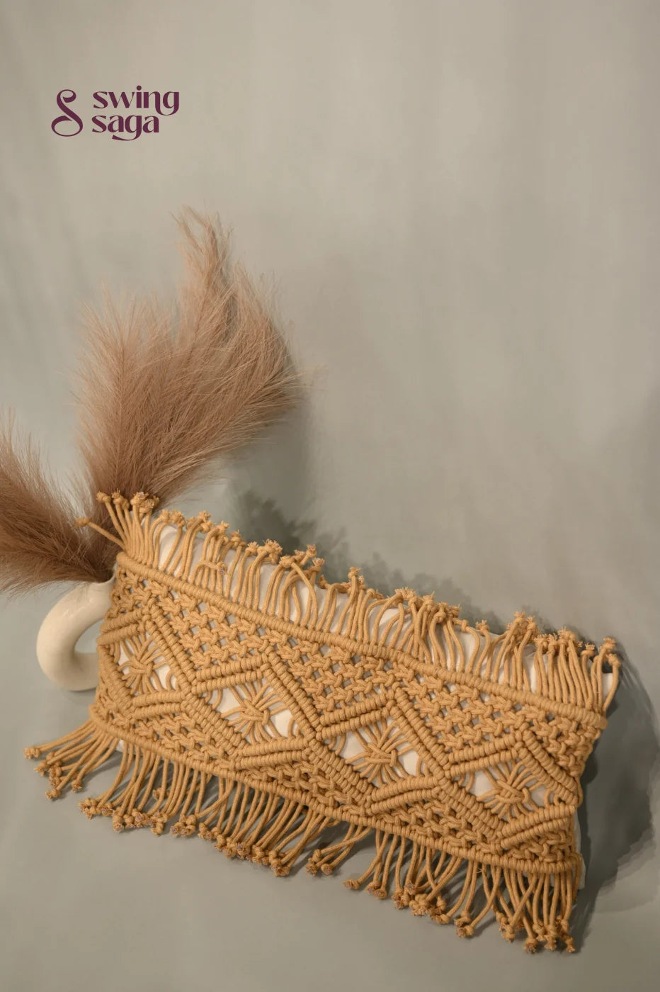 Macrame clutch with fringes and feathers on a neutral background
