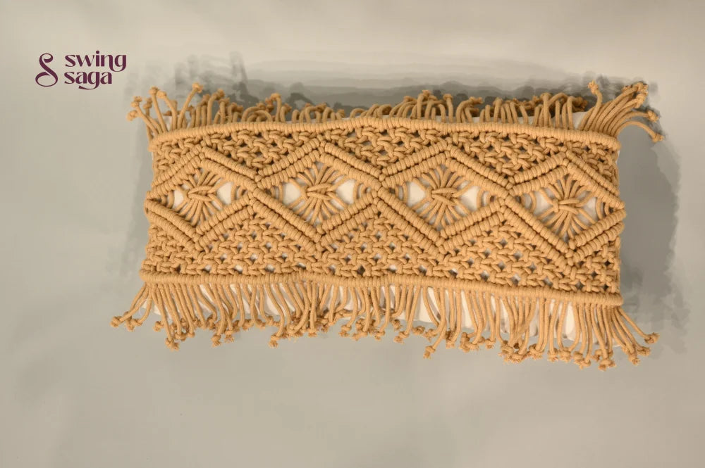 Decorative macrame wall hanging with geometric pattern and fringes on a plain background