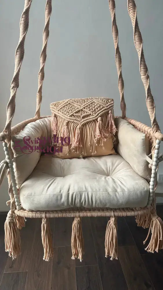 Hanging chair hammock swing with white mattress and peach cushion.