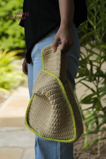 A girl holding a beige color bag with green border for casual outings.