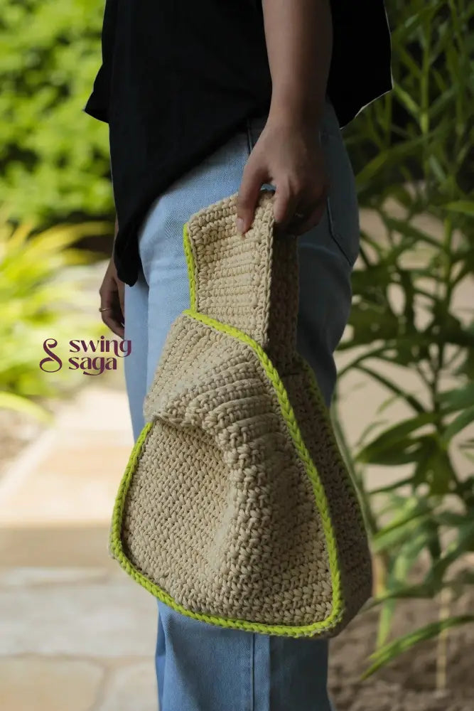 A girl holding a beige color bag with green border for casual outings.
