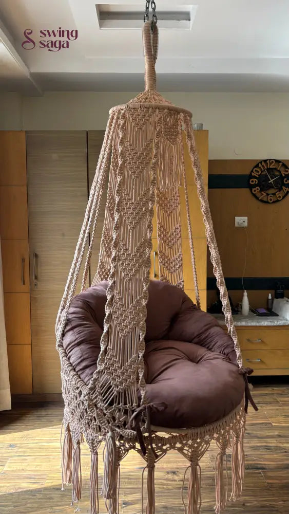 Hanging hammock swing with brown mattress and cushion in a room sertting.